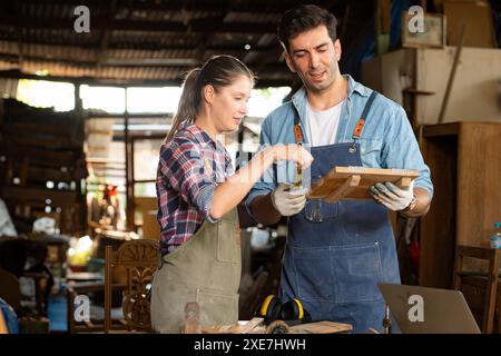 Carpenter e il suo assistente lavorano insieme in un'officina di falegnameria Foto Stock