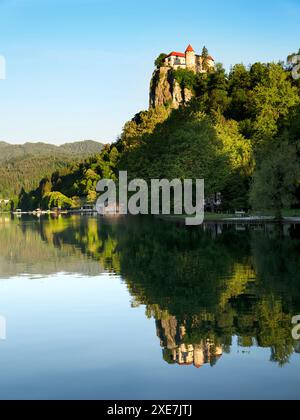 Il castello di Bled illuminato dal sole della mattina presto si riflette nel lago Bled Bled, alta Carniola Slovenia Foto Stock