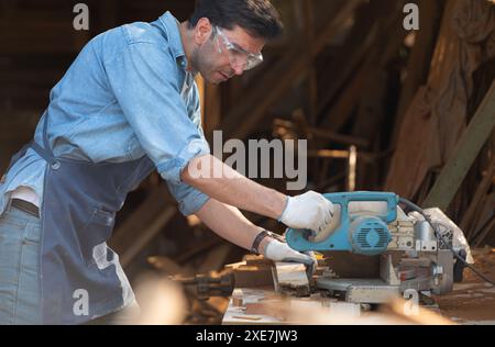 Ritratto di un artigiano che lavora con una sega circolare in un'officina del legno Foto Stock