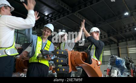 Gruppo di ingegneri e tecnici che lavorano insieme in una fabbrica di bracci robotici. Ispezione del braccio del robot prima della consegna al cliente Foto Stock