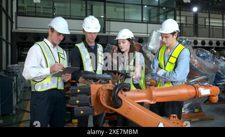 Gruppo di ingegneri e tecnici che lavorano insieme in una fabbrica di bracci robotici. Ispezione del braccio del robot prima della consegna al cliente Foto Stock