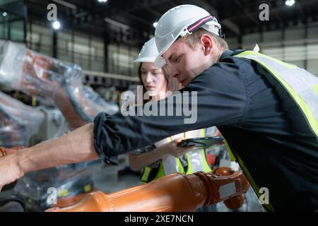 Entrambi gli ingegneri che lavorano insieme in una fabbrica di bracci robotici, nell'industria dei bracci robotici e nel concetto di ingegneria. Foto Stock