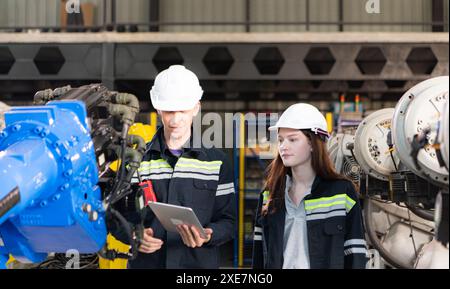 Entrambi gli ingegneri che lavorano insieme in una fabbrica di bracci robotici, nell'industria dei bracci robotici e nel concetto di ingegneria. Foto Stock