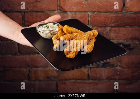 Pepite croccanti di pollo sul piatto nero Foto Stock