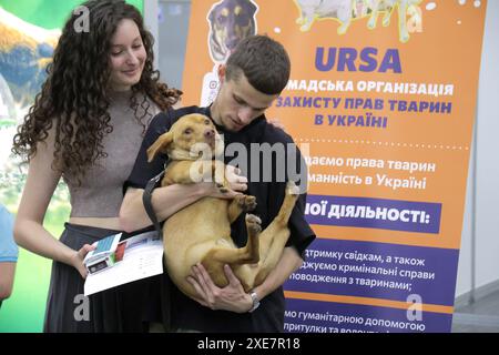 KIEV, UCRAINA - 22 GIUGNO 2024 - Un uomo tiene un cane durante l'evento della giornata dell'adozione presso il Centro esposizioni Internazionale di Kiev, capitale dell'Ucraina. Foto Stock