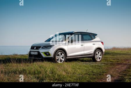 IL SEDILE Arona, parcheggiato su un'erba su un lato di strada sterrata vicino al mare. Vista frontale di tre quarti del crossover in berlina spagnola. Foto Stock