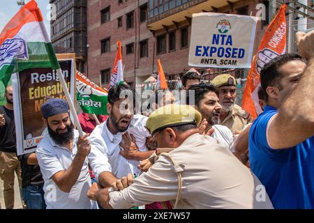 Srinagar, India. 26 giugno 2024. Un poliziotto indiano ferma gli operai del partito del Congresso Nazionale della Gioventù del Kashmir e Jammu mentre protestano contro una presunta truffa negli esami medici nazionali NEET, che sono tenuti dalla National Testing Agency (NTA). Protestano contro le irregolarità del governo e le fughe di carta, insieme a un forte aumento della lista dei meriti del prestigioso esame, in cui 67 studenti senza precedenti stanno segnando il 100% nella storia dell'agenzia di test. Credito: SOPA Images Limited/Alamy Live News Foto Stock