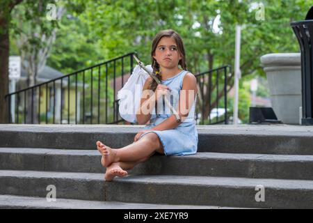 Un bambino scappato abbandonato affamato cerca cibo e riparo in un ambiente all'aperto Foto Stock