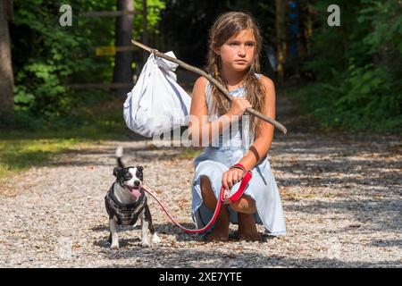 Un bambino scappato abbandonato affamato senza casa cerca cibo e riparo con il suo piccolo cane Foto Stock