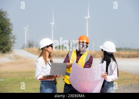 Gruppo di ingegneri e architetti in cantiere con turbine eoliche in background Foto Stock