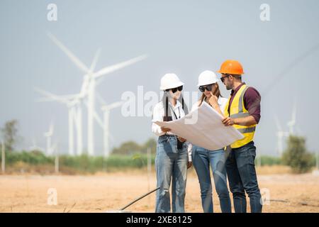 Gruppo di ingegneri e architetti in cantiere con turbine eoliche in background Foto Stock