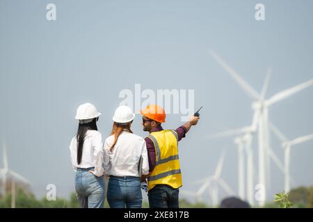 Vista posteriore di ingegneri e architetti del gruppo in cantiere con turbine eoliche sullo sfondo Foto Stock