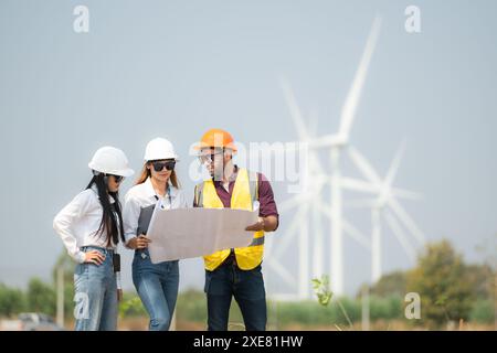 Gruppo di ingegneri e architetti in cantiere con turbine eoliche in background Foto Stock