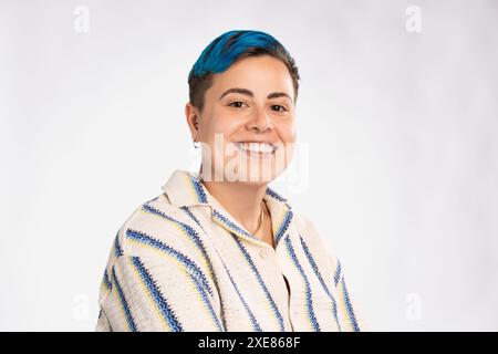 Persona sorridente androgina con capelli blu in modo informale - espressione amichevole e inclusiva, look moderno e vibrante - sfondo semplice, diversit Foto Stock