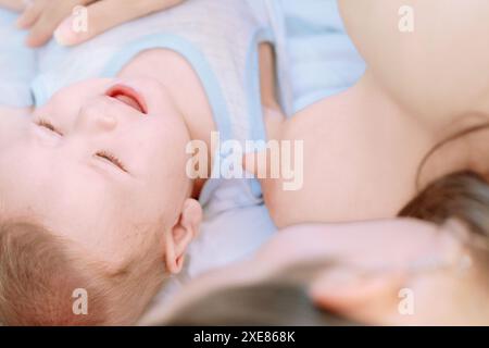 Madre che allatta amorevolmente il suo bambino appena nato. Creando un bellissimo momento di connessione e tenerezza. La scena mostra il legame nutriente tra di noi Foto Stock