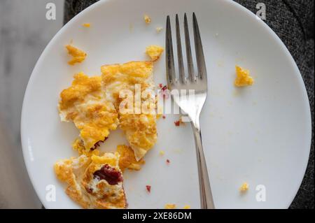 Omelette all'uovo con prosciutto sul piatto bianco e sulla forchetta Foto Stock