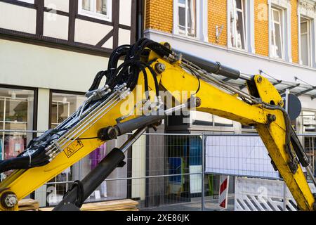 Parte idraulica del braccio di un escavatore giallo sullo sfondo di edifici cittadini. Foto Stock