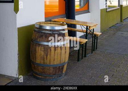 Tavolo in legno con panche e botte di legno vicino ad un caffè sulla strada. Foto Stock