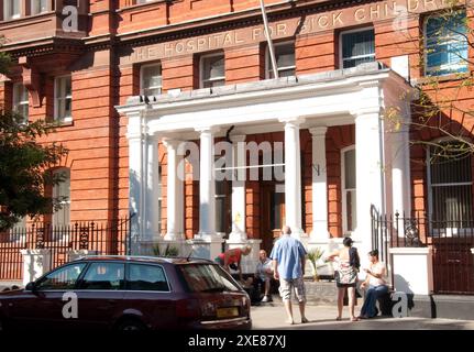Ingresso al Great Ormond Street Hospital for Sick Children - il primo ospedale per bambini costruito in Gran Bretagna, persone sedute e chiacchierate all'esterno Foto Stock