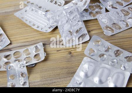 Pile di confezioni di pillole vuote usate, confezioni di medicinali d'argento su un tavolo di legno. Concetto di trattamento, farmaco e uso eccessivo. Foto Stock