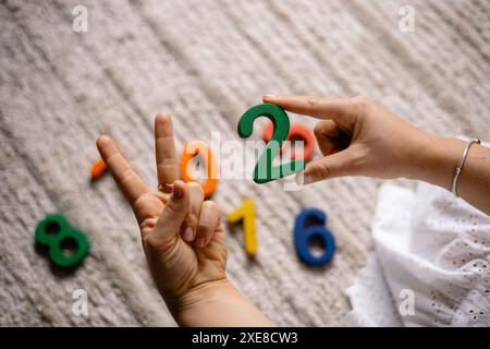 giovane donna che tiene in mano numeri di legno multicolore Foto Stock