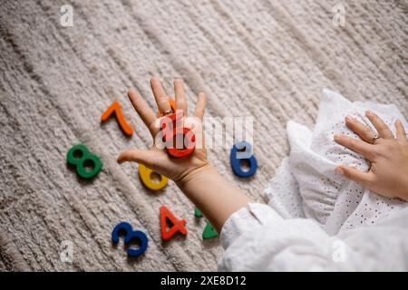 giovane donna che tiene in mano numeri di legno multicolore Foto Stock