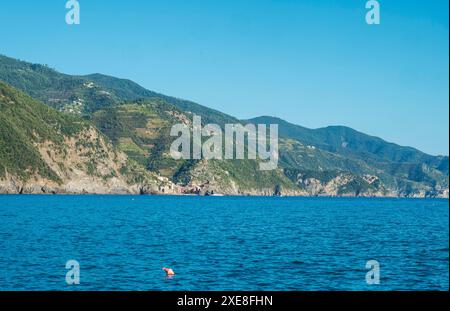 Vista costiera dalla distanza della costa delle cinque Terre con Vernazza e Corniglia villaggi del Parco Nazionale con mare ligure e cielo azzurro. La S Foto Stock