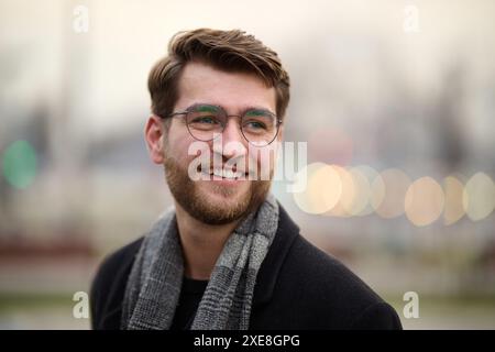 Un bel giovane uomo, vestito con un elegante abito, cravatta e occhiali, trasuda l'aspetto di un uomo d'affari serio e sicuro di sé Foto Stock
