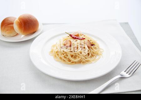 spaghetti aglio olio peperoncino con pane in tavola Foto Stock