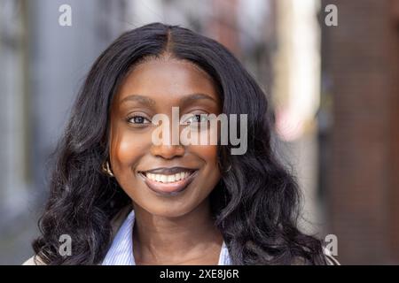 Sorriso radioso di una giovane donna africana in città Foto Stock