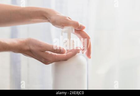 Donna che spinge la pompa con le mani in bottiglia di sapone in plastica su sfondo bianco Foto Stock