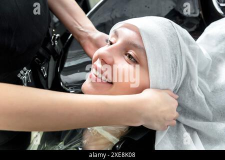 Parrucchiere professionale che asciuga i capelli della donna dopo il lavaggio utilizzando un asciugamano presso il salone di parrucchiere Foto Stock