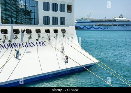 In mare. 25 giugno 2024: I membri dell'equipaggio che lavorano eseguono la manutenzione e la verniciatura dello scafo sulla poppa di una gigantesca nave da crociera, personale dotato di imbracature di sicurezza con gancio. La sicurezza a bordo delle navi e' il 14° giorno del tema del marittimo. L'Organizzazione marittima internazionale (IMO) lancia una campagna che mette in evidenza il contributo dei marittimi per rendere il settore marittimo un luogo di lavoro più sicuro. Questo giorno per onorare tutti i marinai è stato adottato dalla Conferenza diplomatica 2010 a Manila, Filippine, per rivedere STCW (Standards of Training, Certification & Watchkeeping Convention). Crediti: Kevin Izorce/Alamy Live News Foto Stock