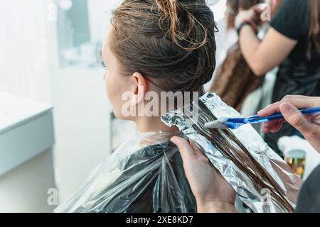 Donna che ha i capelli sventati mentre colorano nel parrucchiere Foto Stock