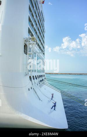 In mare. 25 giugno 2024: I membri dell'equipaggio che lavorano eseguono la manutenzione e la verniciatura dello scafo sulla poppa di una gigantesca nave da crociera, personale dotato di imbracature di sicurezza con gancio. La sicurezza a bordo delle navi e' il 14° giorno del tema del marittimo. L'Organizzazione marittima internazionale (IMO) lancia una campagna che mette in evidenza il contributo dei marittimi per rendere il settore marittimo un luogo di lavoro più sicuro. Questo giorno per onorare tutti i marinai è stato adottato dalla Conferenza diplomatica 2010 a Manila, Filippine, per rivedere STCW (Standards of Training, Certification & Watchkeeping Convention). Crediti: Kevin Izorce/Alamy Live News Foto Stock