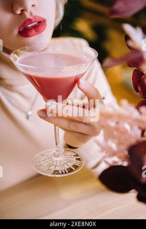 La giovane donna beve un cocktail rosso con fragole Foto Stock