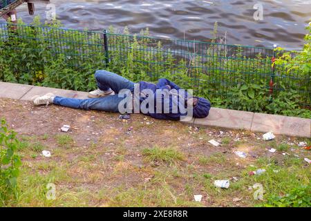 Berlino, Germania - 21 maggio 2024: Un senzatetto dorme sull'argine tra la spazzatura Foto Stock