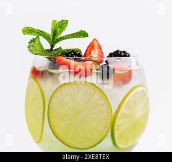 Bere con i frutti di bosco, con fette di lime e menta in un bicchiere di vino Foto Stock