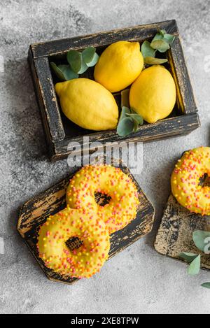 Deliziose ciambelle fresche in smalto giallo con sapore di limone ripieno su fondo in cemento Foto Stock