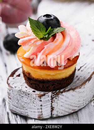 Cupcake al cioccolato con panna rosa e mirtillo fresco Foto Stock