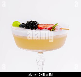 Primo piano cocktail giallo con schiuma bianca e frutti di bosco Foto Stock