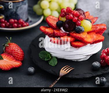 Mini torta di meringa pavlova decorata con frutti di bosco freschi Foto Stock