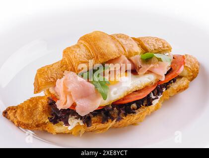 Colazione con panini con croissant, uova fritte e salmone Foto Stock