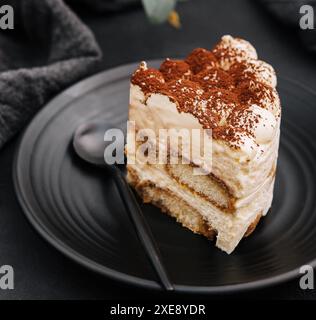 Tradizionale tiramisù italiano su piatto nero Foto Stock