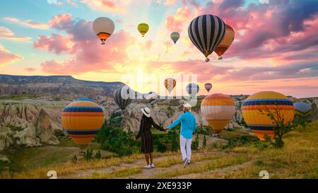 Felice giovane coppia durante l'alba guardando le mongolfiere di Kapadokya Cappadocia Turchia Foto Stock