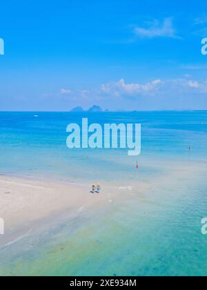 Un paio di uomini e donne camminano in spiaggia durante una vacanza tropicale in Thailandia Foto Stock