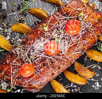 Gustoso filetto di maiale al forno in glassa miele-arancia con spicchi di patate Foto Stock