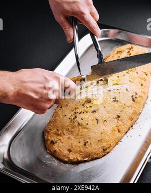 Pesce al forno, ripieno di erbe aromatiche, in crosta di sale tagliata dallo chef Foto Stock