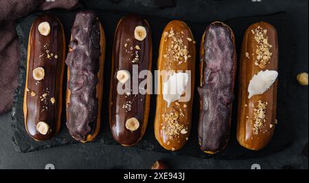 Dolci eclari di cioccolato su tavola di legno nera Foto Stock