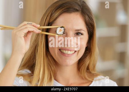 una giovane donna copre gli occhi con sushi roll Foto Stock